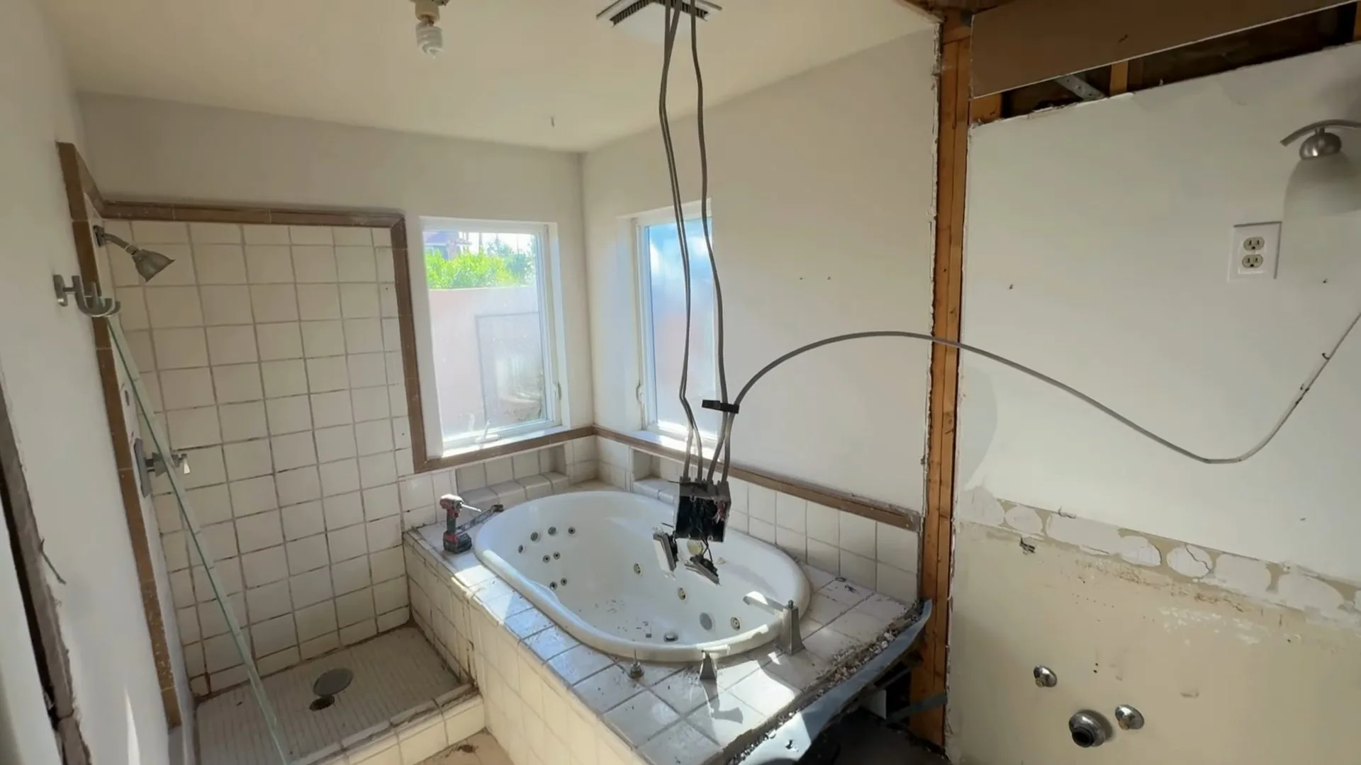 Gutted bathroom with a tub, a tiled shower wall and open wall studs
