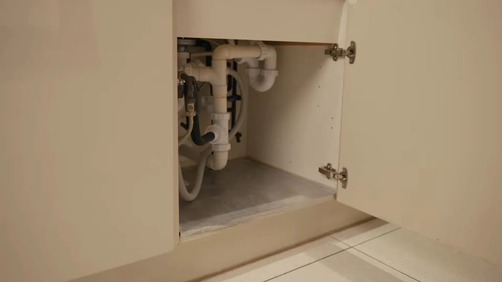 Open under-sink cabinet showing a drain trap and supply connections