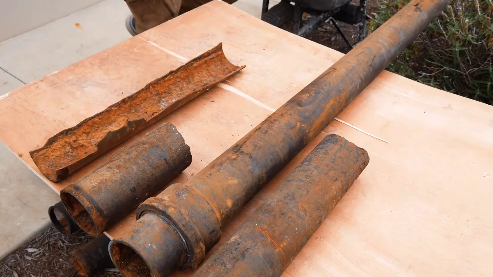 Cut sections of rusted galvanized pipe laid out on a wooden board